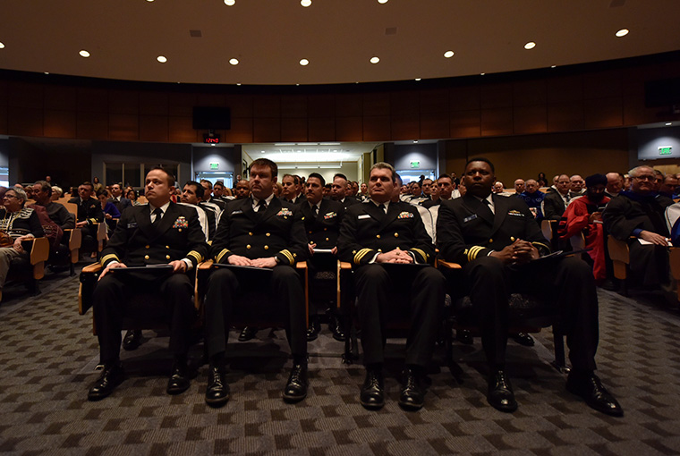 Graduates sit with their diplomas during U.S. Naval War College's graduation ceremony in Spruance Auditorium.