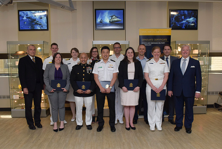 Students in the Ethics and Emerging Military Technology program stand together for a group photo in U.S. Naval War College’s Future Forces Gallery.