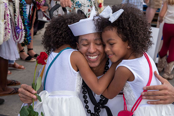 Fire Control Technician 1st Class Quincy Miller, from Savannah, Georgia, assigned to the Virginia-class fast-attack submarine USS Texas (SSN 775), embraces his family during Texas' homecoming.