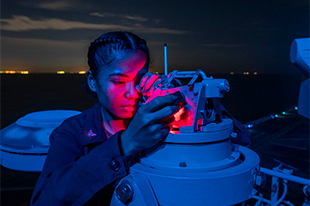 Quartermaster 3rd Class Orpha Hapdei, from Yap, Micronesia, uses a telescopic alidade aboard the amphibious assault ship USS Essex (LHD 2) during strait transit operations, Jan. 11, 2022.