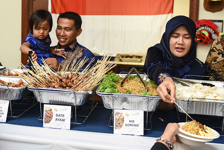 Indonesian naval officer Lt. Cmdr. Ahmad Ikhlas, his daughter, Nayra, and wife, Nisa, serve Indonesian food as part of their country presentation to classmates in the Naval Staff College.