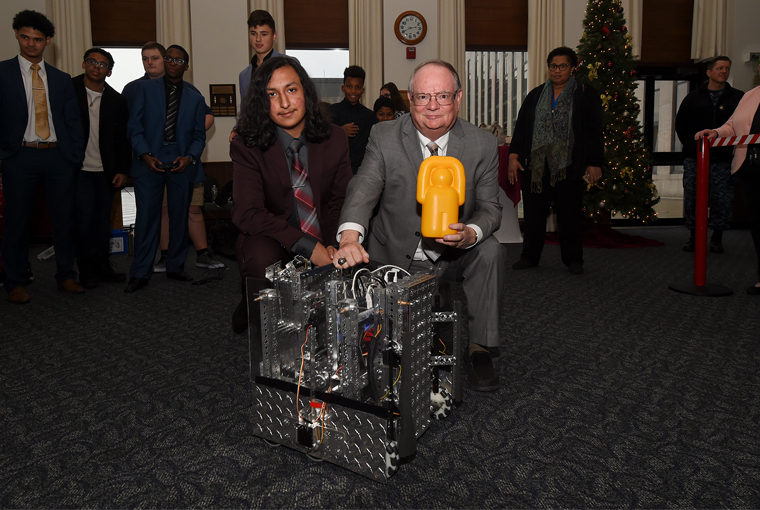 John Jackson (right), a U.S. Naval War College (NWC) professor and E.A. Sperry Chair of Unmanned and Robotic Systems and Omar Martinez, an 11th grader, pose with one of the robotics team at Pawtucket, Rhode Island’s Slater Junior High School and Shea High School.